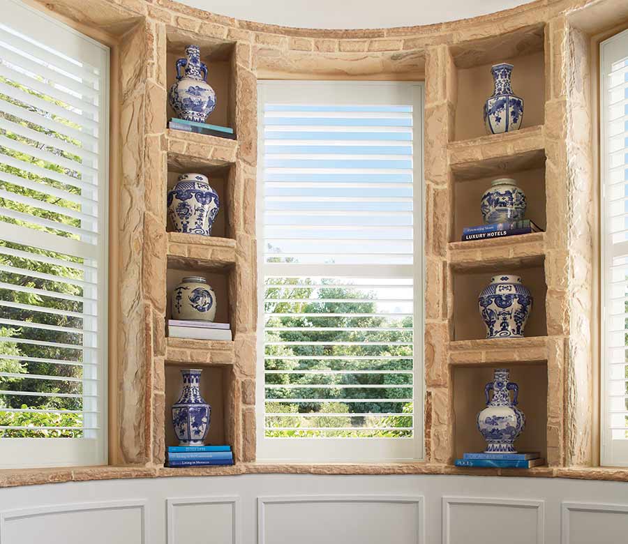 white palm beach shutters in living room by built in shelves