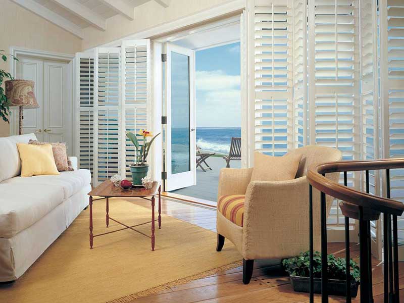 custom wood shutters at night and day opening up to outside patio