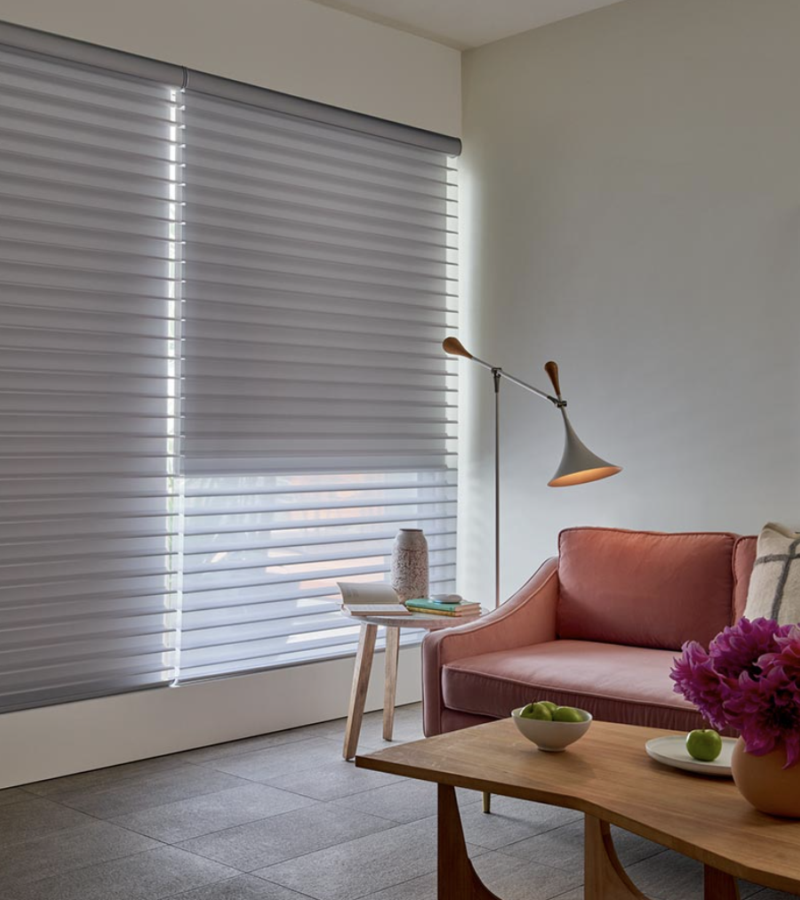 Silhouette® Shades covering windows with a plush, velvet couch and a floor lamp.